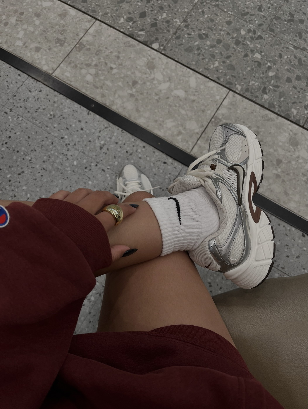 woman wearing burgundy sweatshirt and nike's with one foot crossed over her knee